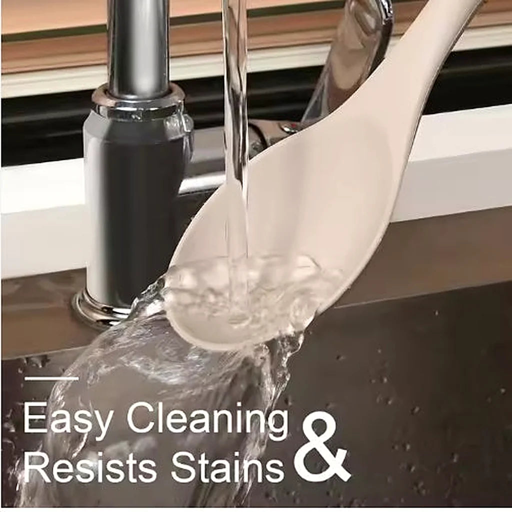 Khaki silicone serving spoon being rinsed under running water at a kitchen sink faucet