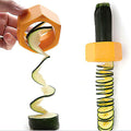 Hand twisting the orange spiral cutter on a zucchini to make a long spiral ribbon, with a spiral-cut zucchini beside it