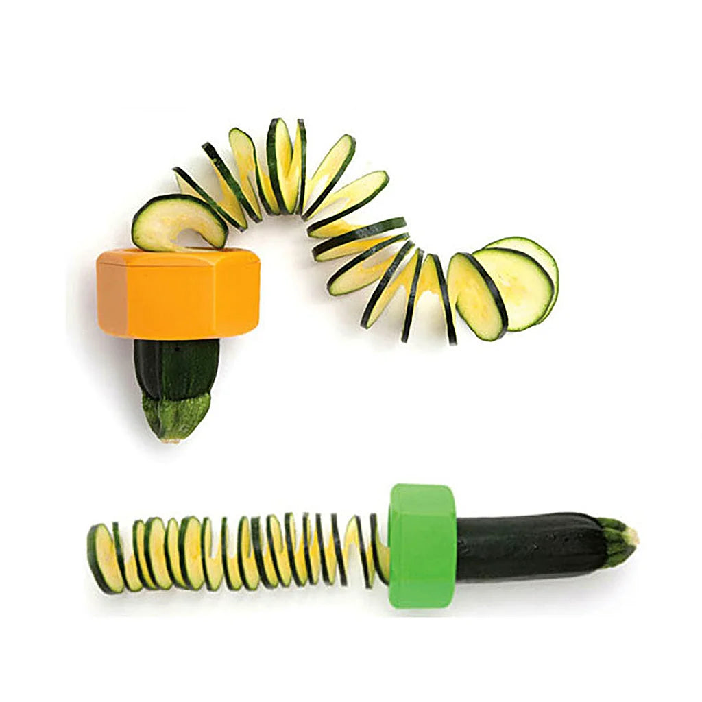 Orange and green spiral cutters with zucchini sliced into connected spirals, arranged in an arc and a row on white