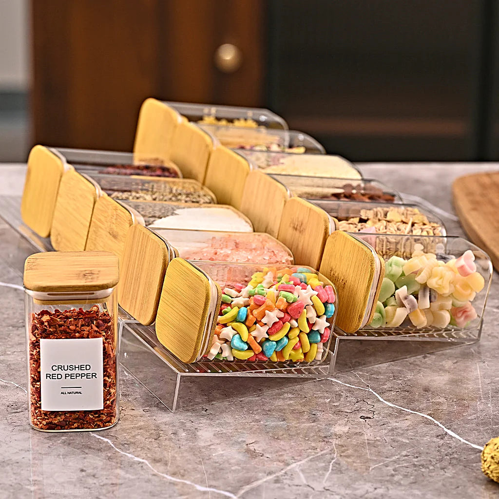 Side view of two tiered spice racks with tilted jars on a marble counter, one labeled jar standing in front