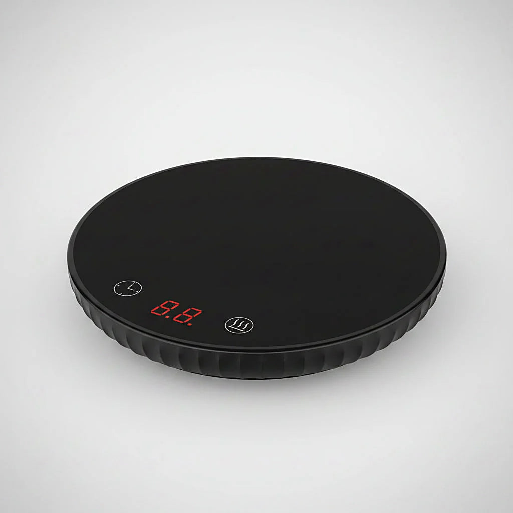 Black round mug warmer with touch controls and a red digital display on a light gray background