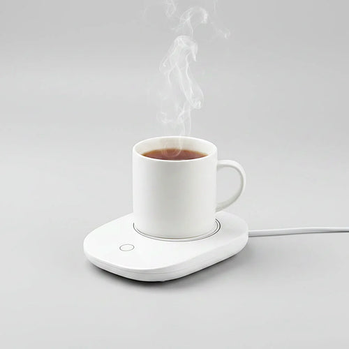 A white electric mug warmer holding a white ceramic mug filled with tea, with steam rising, on a light gray background.